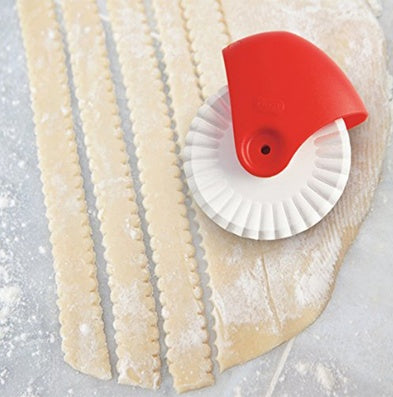 A red and white plastic pastry lattice dough cutter with a roller wheel, designed for creating decorative lattice patterns on pizza, pies, and quiches.