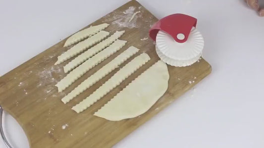 A red and white plastic pastry lattice dough cutter with a roller wheel, designed for creating decorative lattice patterns on pizza, pies, and quiches.