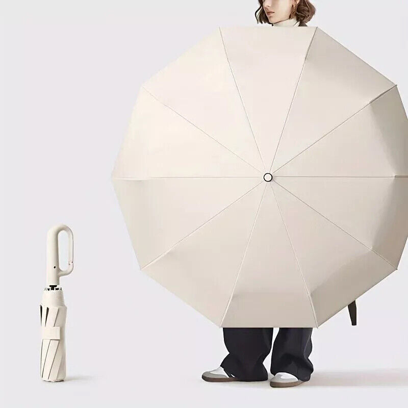Person holding a large beige umbrella with a smaller matching umbrella on the ground.