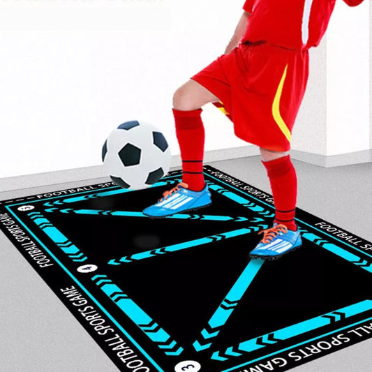 Person in red sports outfit playing on a large interactive sports game mat with a soccer ball.